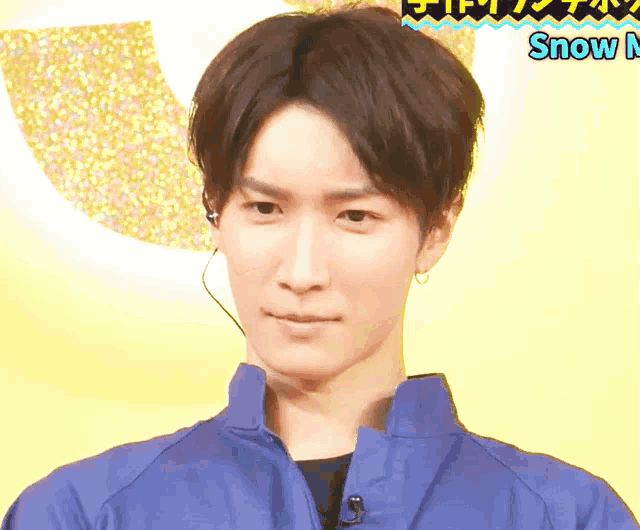 a man wearing a blue jacket and a microphone stands in front of a yellow background with the word snow on it