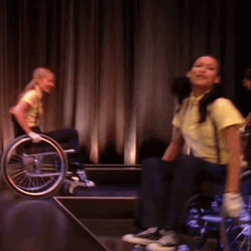 a woman in a yellow shirt is smiling while sitting in a wheelchair