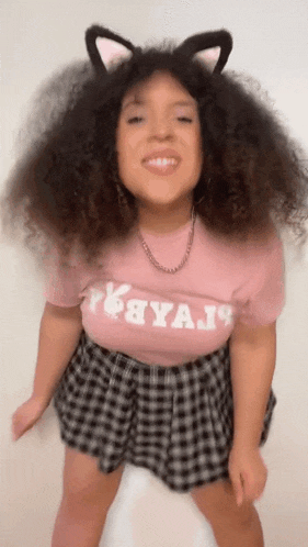a woman wearing cat ears and a pink t-shirt is dancing .