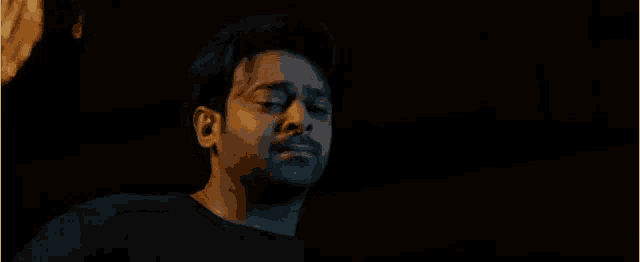 a close up of a man 's face in a dark room with his eyes closed .
