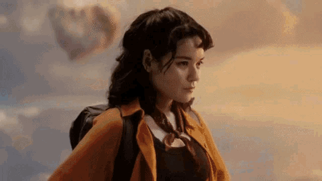 a woman with a backpack is standing in front of a hot air balloon in the sky .