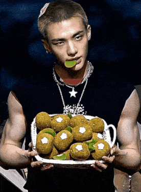 a man with a star necklace is holding a plate of food