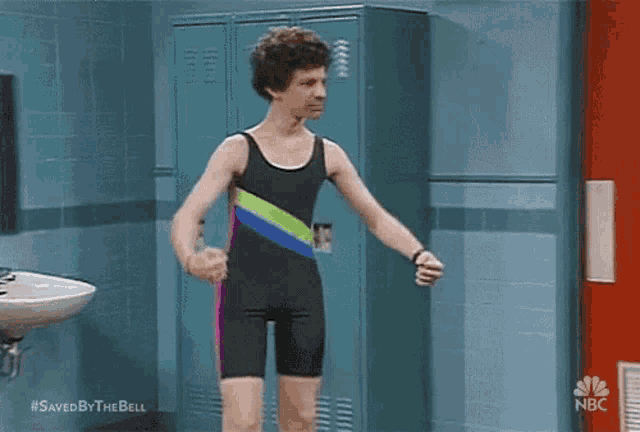 a man in a bathing suit is standing in a bathroom next to a sink and lockers .