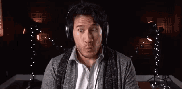 a man wearing headphones is sitting in front of a microphone in a dark room .