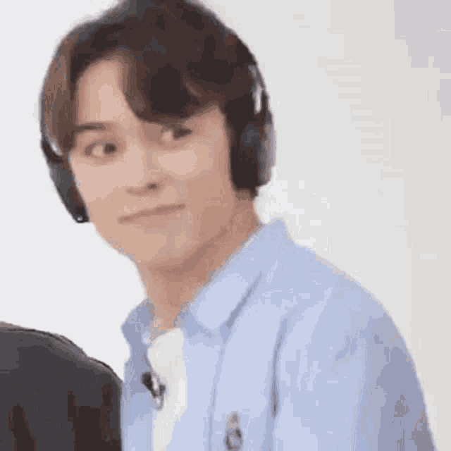 a young man is wearing headphones and making a funny face .