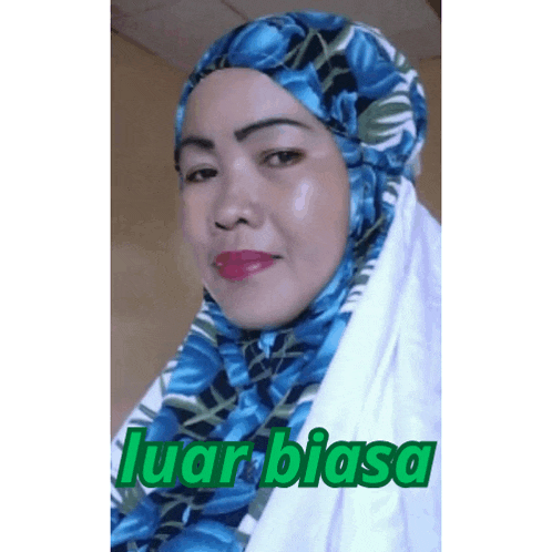 a woman wearing a blue and white hijab with the words luar biasa written on the bottom