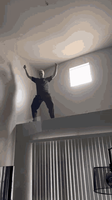 a man is jumping in the air while standing on a ledge in front of a window