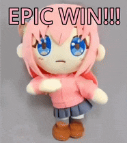 a stuffed doll with pink hair and blue eyes is standing on a table .