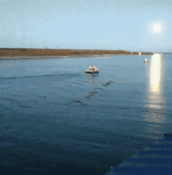 a boat is floating on a body of water with a full moon behind it