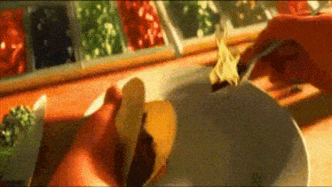 a person is putting a tortilla in a bowl of sauce .