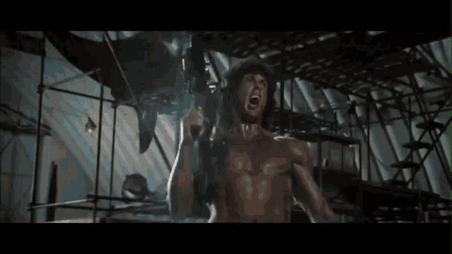 a man with a shaved head is screaming in a dark room .