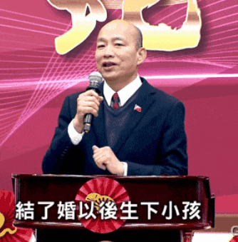 a man stands at a podium holding a microphone with chinese writing on it