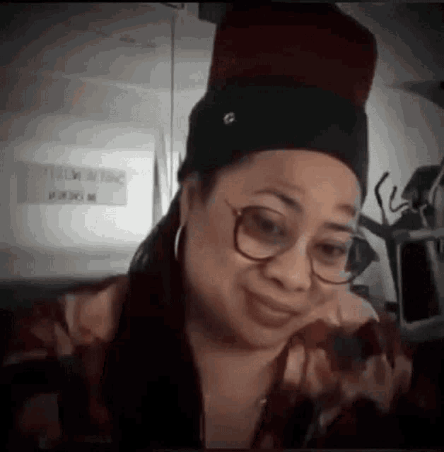 a woman wearing glasses and a hat is sitting in front of a computer .
