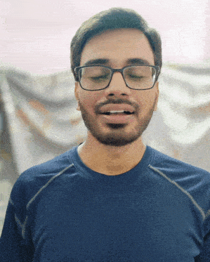 a man wearing glasses and a blue shirt making a funny face
