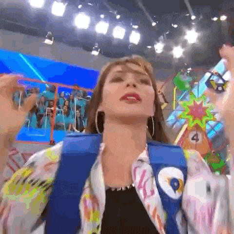 a woman wearing a colorful jacket and earrings is standing in front of a colorful ferris wheel .