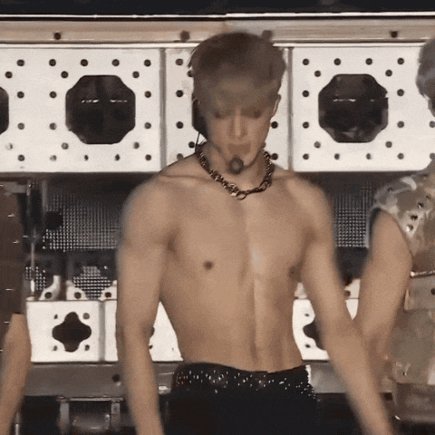 a shirtless man wearing a necklace and headphones is dancing on a stage