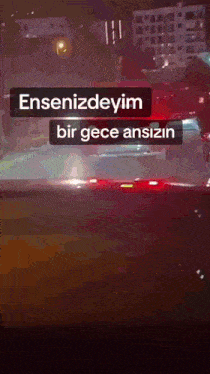 a car is driving down a street at night and the words " ensenizdeyim bir gece ansizin " are displayed
