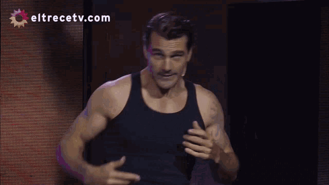 a man in a black tank top stands in front of eltrecetv.com