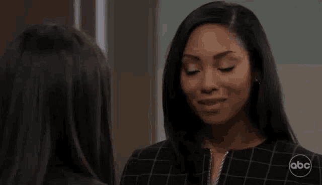 two women are standing next to each other in a room and smiling .