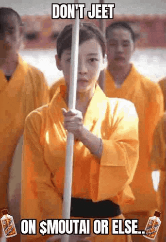 a woman in a yellow kimono is holding a long stick in front of a group of people .