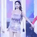 a woman in a silver dress is dancing on stage .