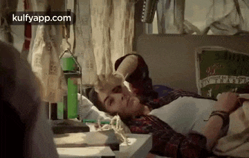 a woman is laying on a bed with her hand on her forehead and a pencil in her hand .