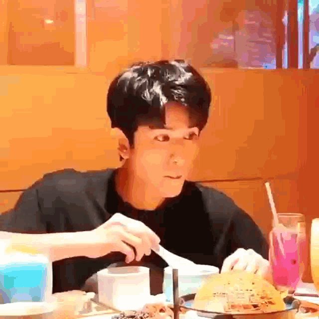 a man is sitting at a table eating food with a fork .
