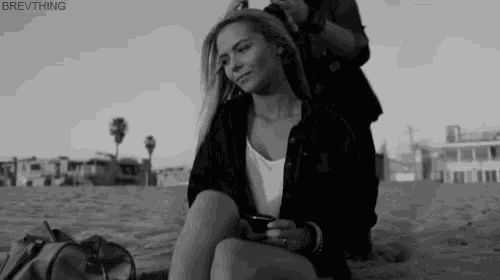 a black and white photo of a woman sitting on a beach with the caption brewthing