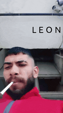 a man with a beard is smoking a cigarette in front of a leon sign