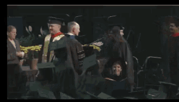 a man in a graduation cap and gown is giving a high five to another man