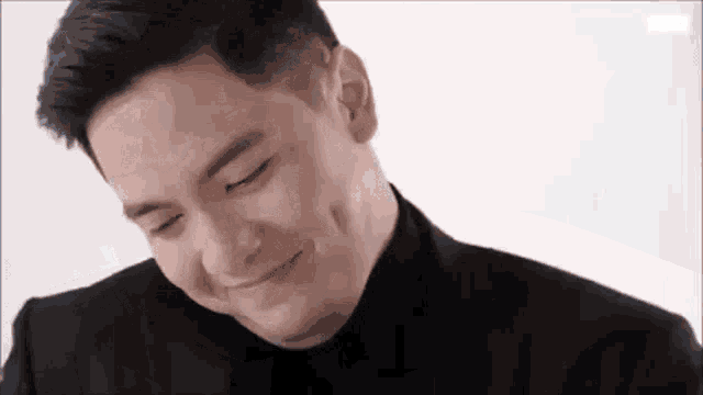 a man in a suit is smiling with his eyes closed and his mouth open .