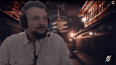 a man wearing headphones and a microphone stands in front of a night scene