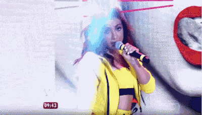 a woman is singing into a microphone in front of a picture of a woman 's lips .