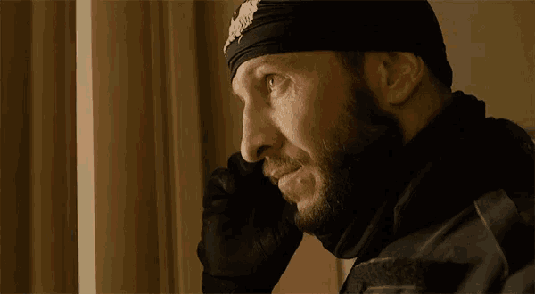 a man with a beard is wearing a bandana that says ' biker ' on it .