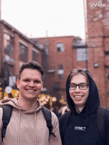 two young men are posing for a picture and one has a hoodie that says ' ihug ' on it