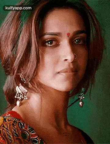 a close up of a woman 's face wearing earrings and a nose ring .
