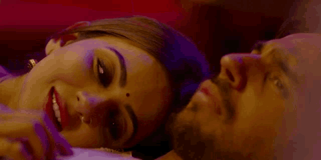 a man and a woman are laying next to each other on a bed and the woman is smiling .