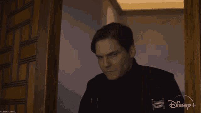 a man in a black shirt is standing in a doorway with a disney logo in the corner