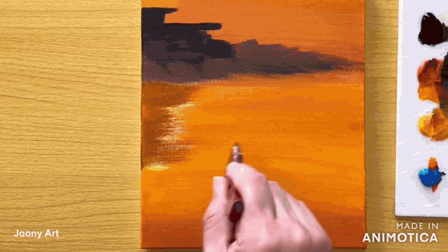 a person is painting a sunset on a canvas with a pen