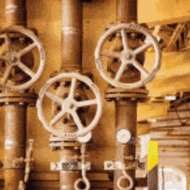 a row of copper pipes with wheels on them and a gauge on the right