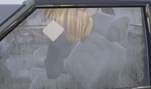 a person with blonde hair is sitting in the back seat of a car looking out the window .