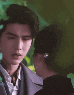 a man in a suit and tie is standing next to a woman in a hat .