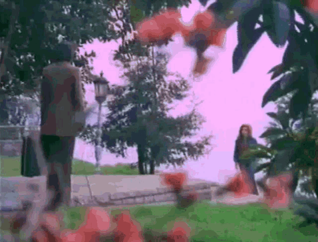 a man and a woman are walking in a park with trees in the background