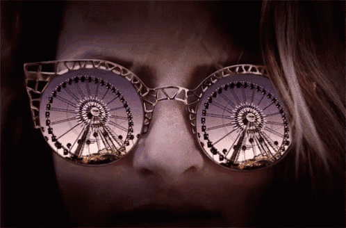 a woman wearing a pair of sunglasses with a ferris wheel reflection