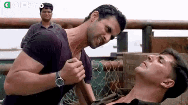 two men are standing next to each other on a boat and fighting .