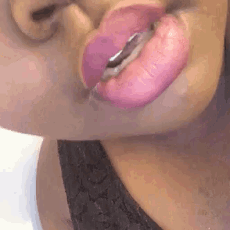 a close up of a woman 's lips with pink lipstick and a gold tongue ring .