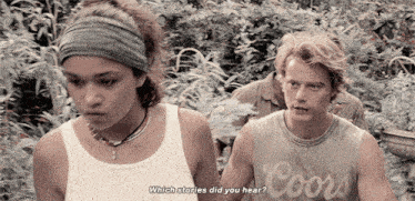 a man wearing a coors tank top is talking to a woman
