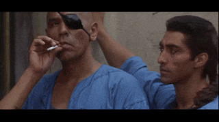 a man with an eye patch smoking a cigarette