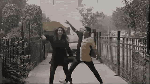 a man and a woman are dancing together on a sidewalk .