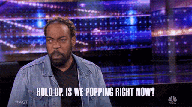 a man in a denim jacket says " hold up is we popping right now " on a stage